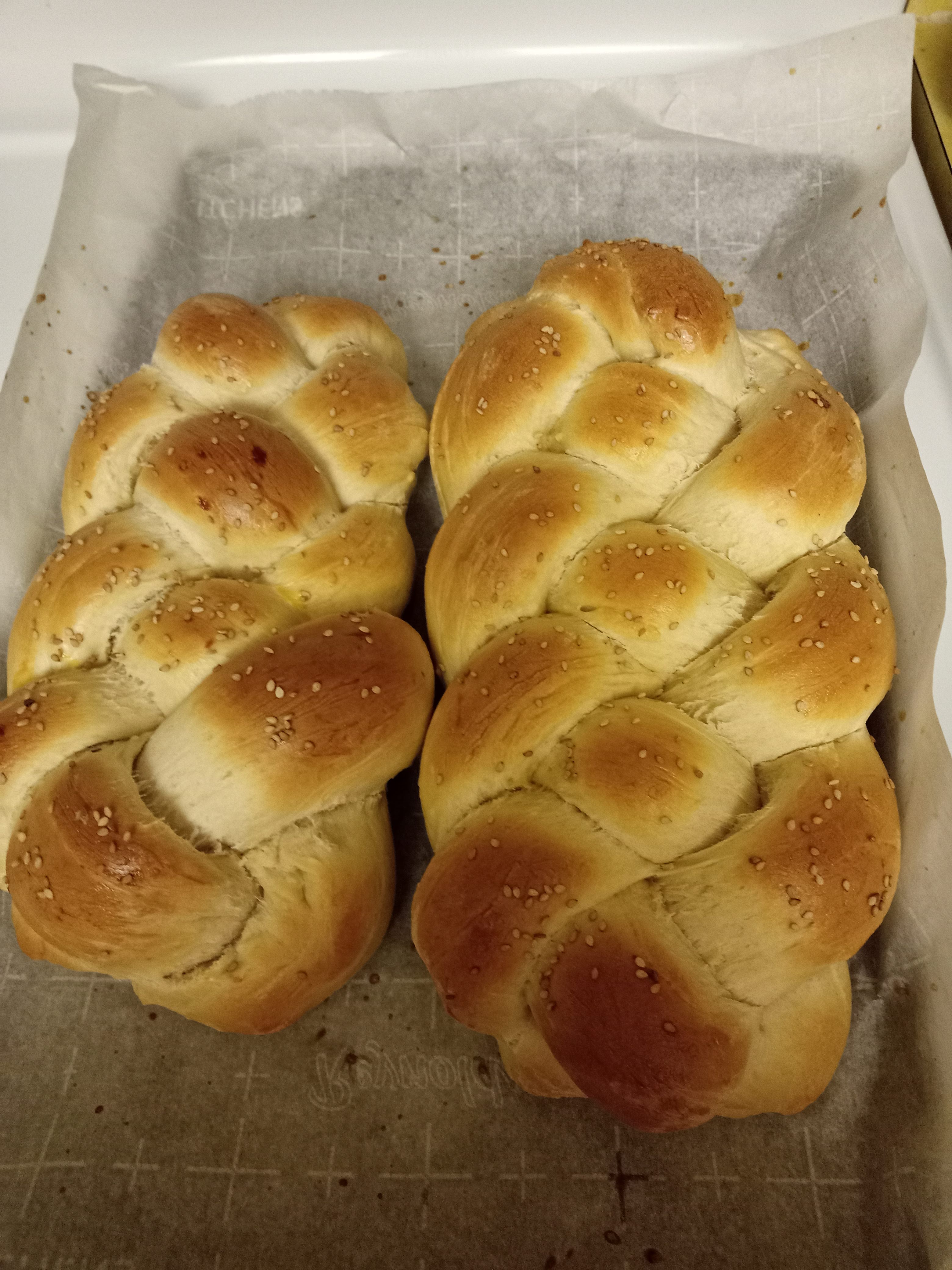 two loaves of braided bread on top of a parchment paper covered baking sheet
