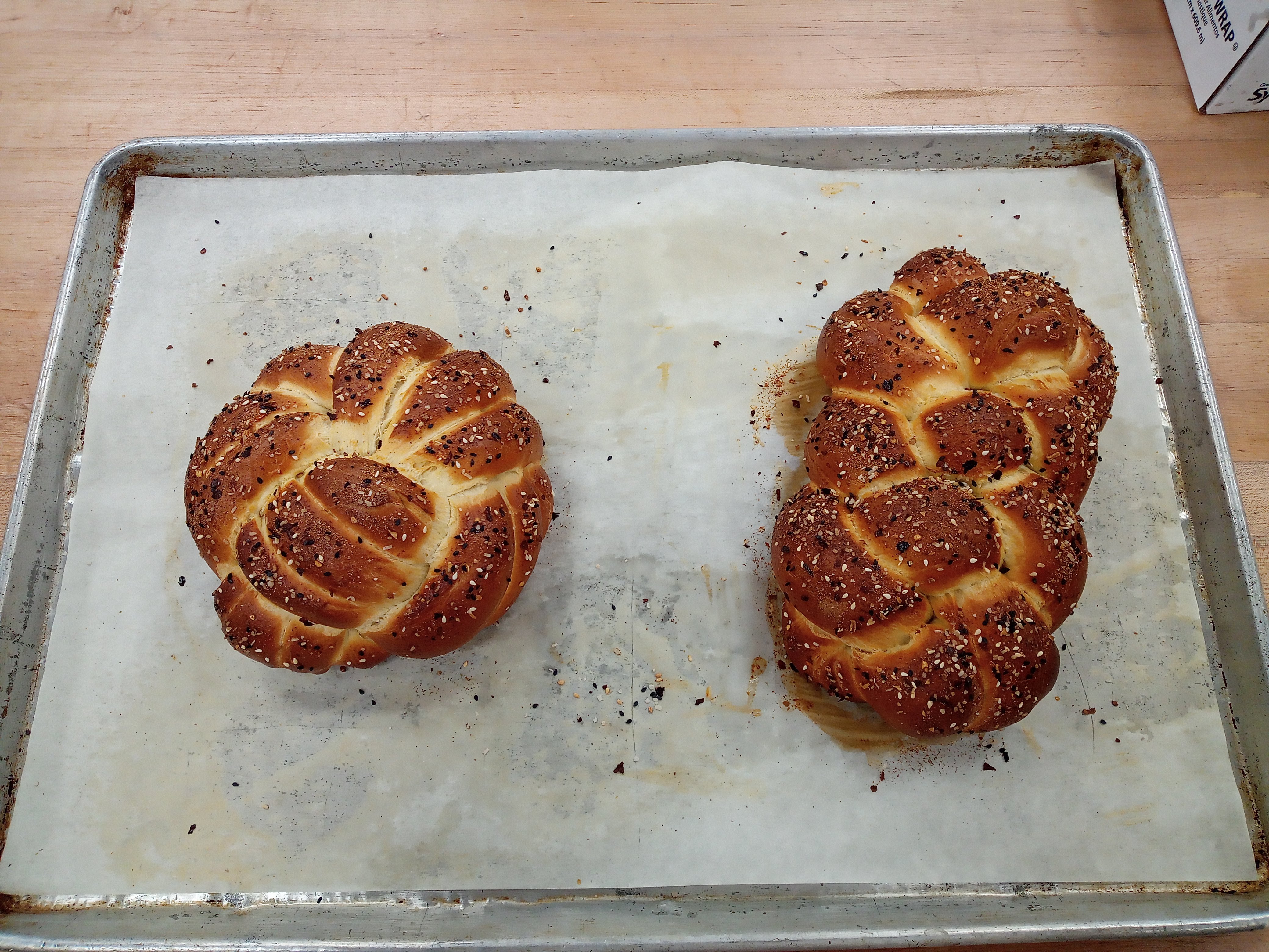 Two loaves of braided bread on a parchment paper covered baking sheet